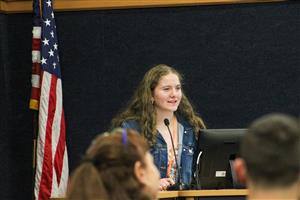 A student giving a presentation to her peers and evaluators. 