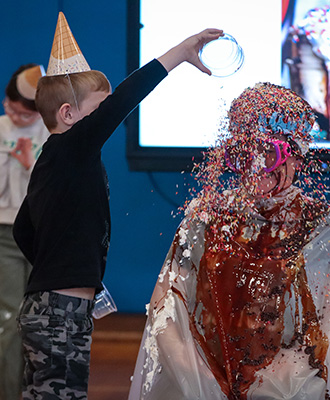  A small boy throwing sprinkles on his principal's head