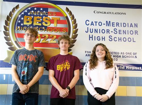 Three students stand in front of a banner in the Junior-Senior High School