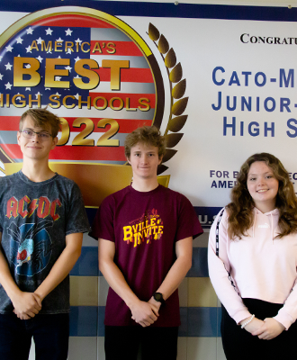 Three students stand in front of a banner in the Junior-Senior High School