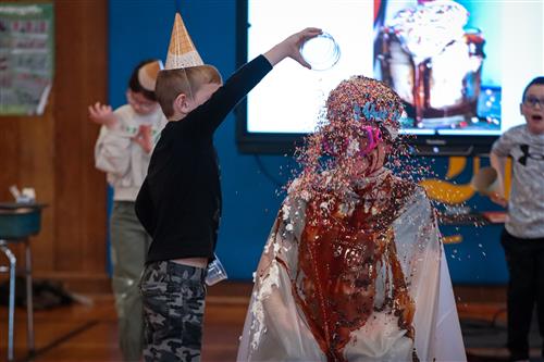 A small boy throwing sprinkles on his principal's face